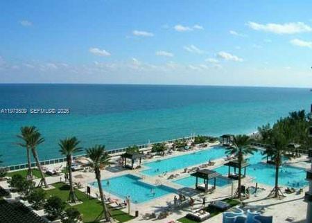 An elevated view of a resort-style swimming pool complex overlooking the ocean — 1800 Ocean Dr # 1408, Hallandale Beach FL 33009, HALLANDALE BEACH, FL