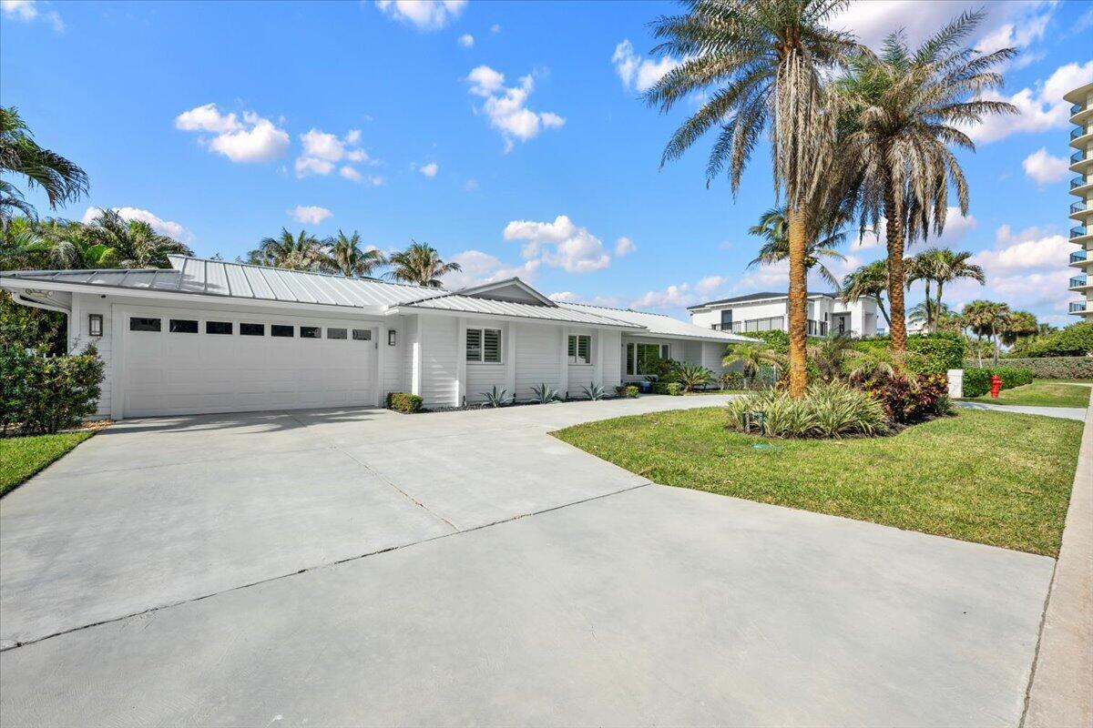 A white single-story house with a metal roof and a large concrete driveway — 48 Ocean Drive, Jupiter FL 33469, JUPITER, FL
