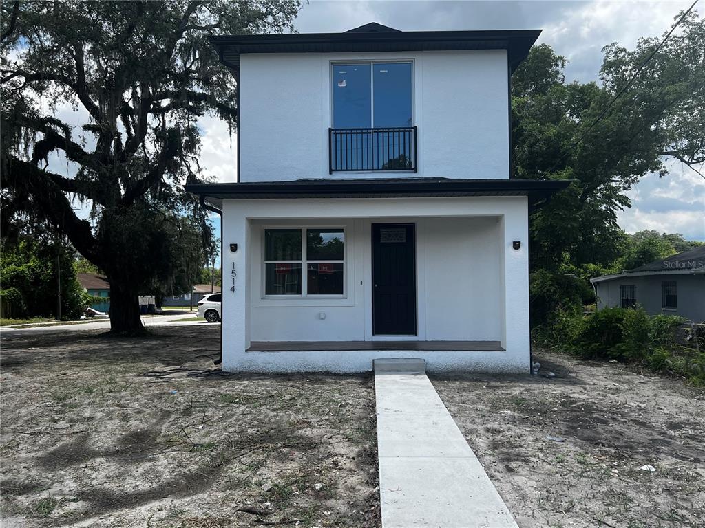 A two-story white house with a covered front porch and a stack of wooden pallets — 1514 E JUNEAU STREET, TAMPA, FL