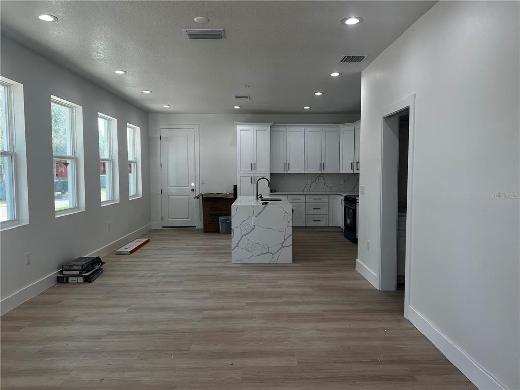 A kitchen features white cabinets, a marble-patterned island, and light wood-look flooring — 1514 E JUNEAU STREET, TAMPA, FL
