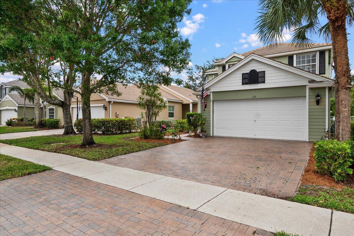 A two-story house with green siding, a white garage door, and a paved driveway — 135 Hamilton Terrace, West Palm Beach FL 33414, WEST PALM BEACH, FL