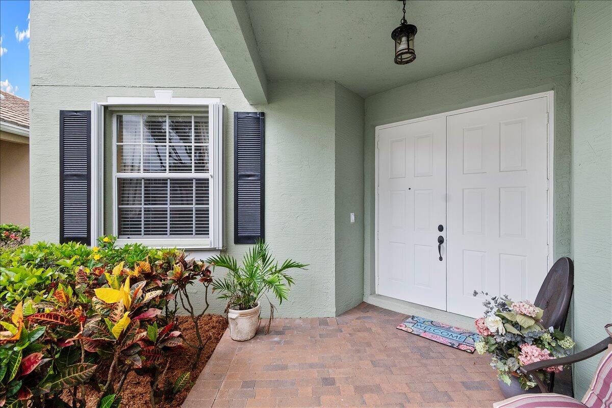A covered entryway features a double white door, a brick floor, and a small garden — 135 Hamilton Terrace, West Palm Beach FL 33414, WEST PALM BEACH, FL