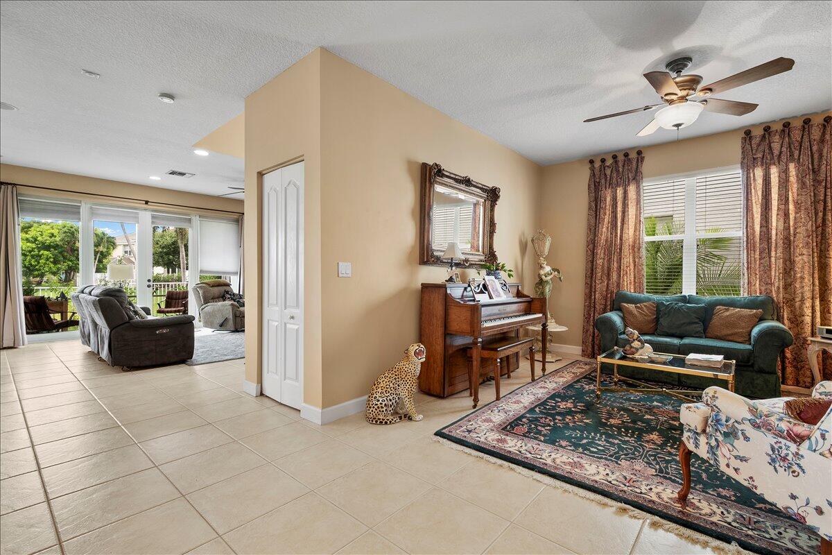 A living room features tile floors, a piano, a patterned rug, and a ceiling fan — 135 Hamilton Terrace, West Palm Beach FL 33414, WEST PALM BEACH, FL