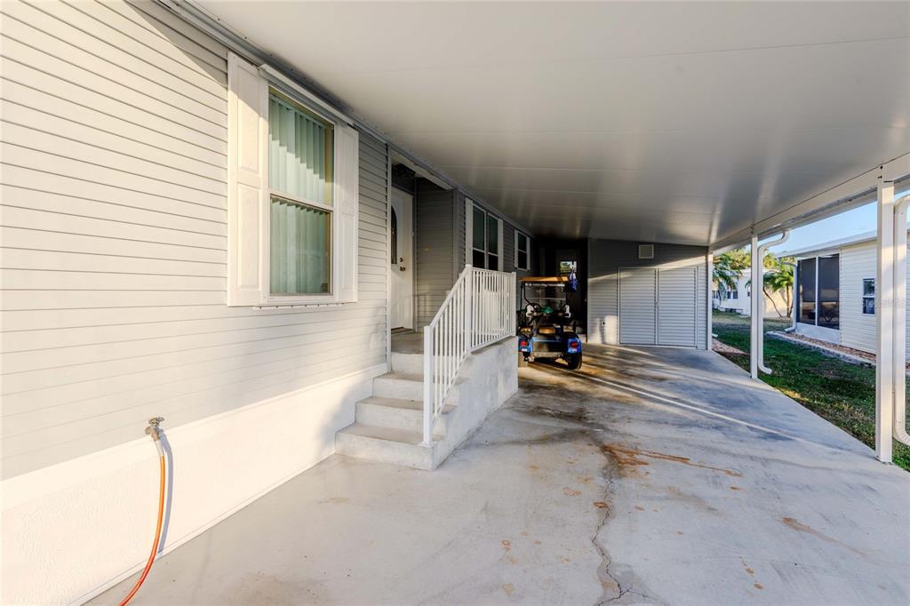 A gray mobile home exterior features a covered carport, concrete steps, and a golf cart — 2100 KINGS HIGHWAY UNIT 437, PUNTA GORDA, FL