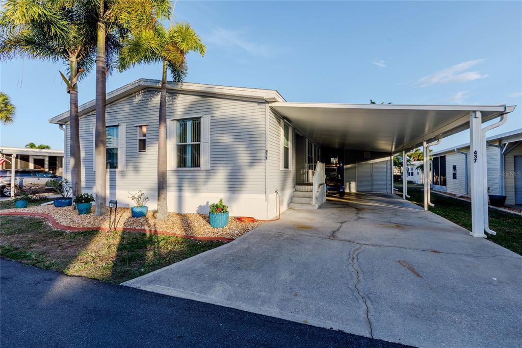 A light gray manufactured home features a concrete driveway and a covered carport — 2100 KINGS HIGHWAY UNIT 437, PUNTA GORDA, FL