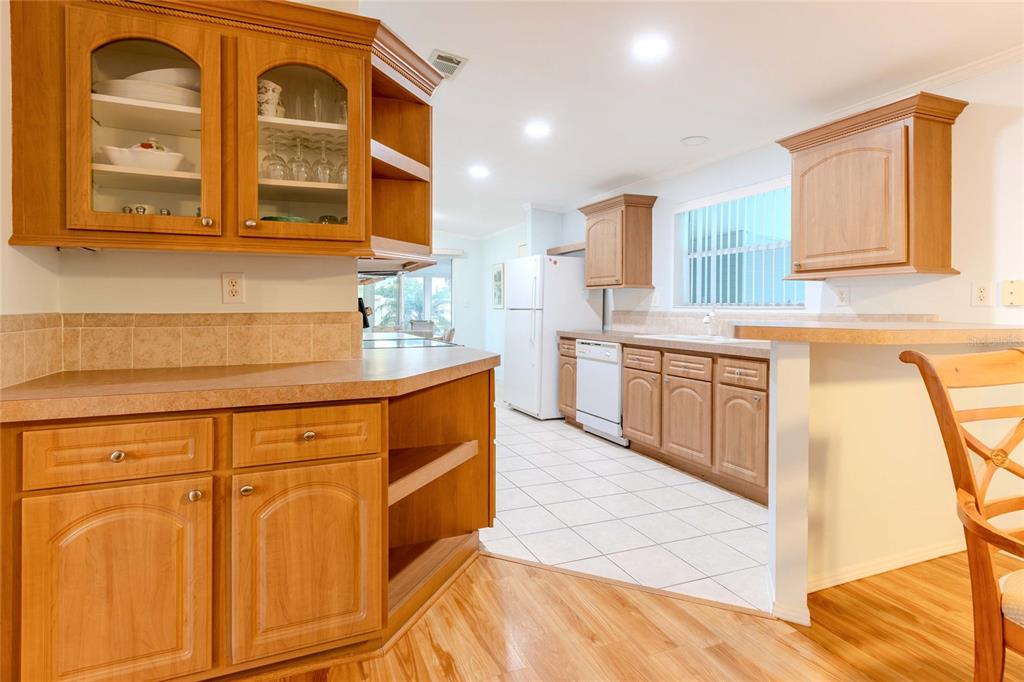 A kitchen features light wood cabinets, laminate countertops, white appliances, and tiled flooring — 2100 KINGS HIGHWAY UNIT 437, PUNTA GORDA, FL