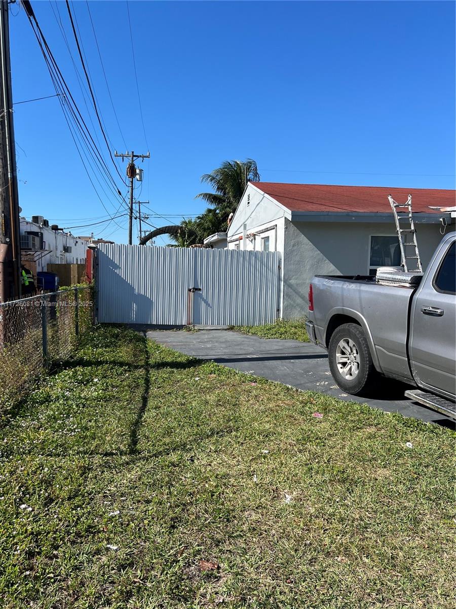 A gray pickup truck is parked on a driveway next to a white metal gate — 720 NW 30th Ave, Miami FL 33125, MIAMI, FL