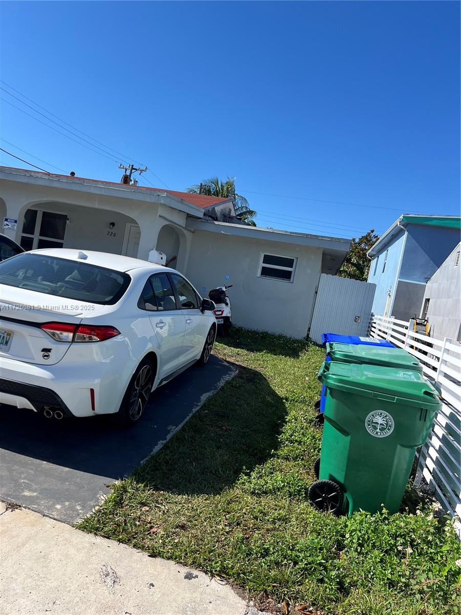A white sedan is parked in the driveway next to two green trash bins — 720 NW 30th Ave, Miami FL 33125, MIAMI, FL