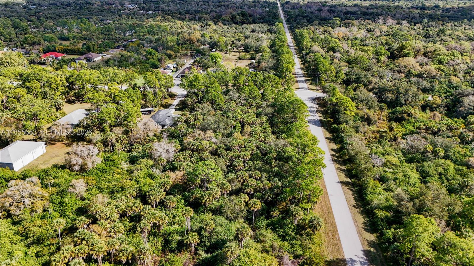 An aerial view shows a paved road running through a dense, wooded residential area — 3132 SE 24 Ave, Naples FL 34117, NAPLES, FL