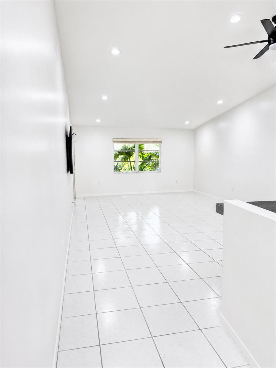 A bright, empty room features white walls, white tiled floors, and a single window — 6356 Pointe Pleasant Circle, Delray Beach FL 33484, DELRAY BEACH, FL