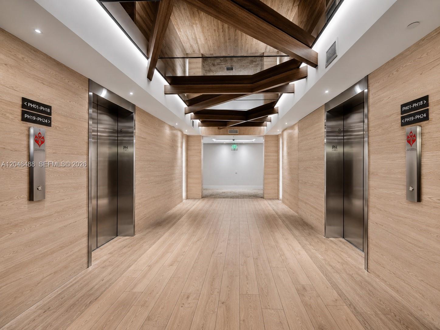 A modern elevator lobby features wood-paneled walls, light wood flooring, and a geometric ceiling design — 2301 Collins Ave, Miami Beach FL 33139, MIAMI BEACH, FL