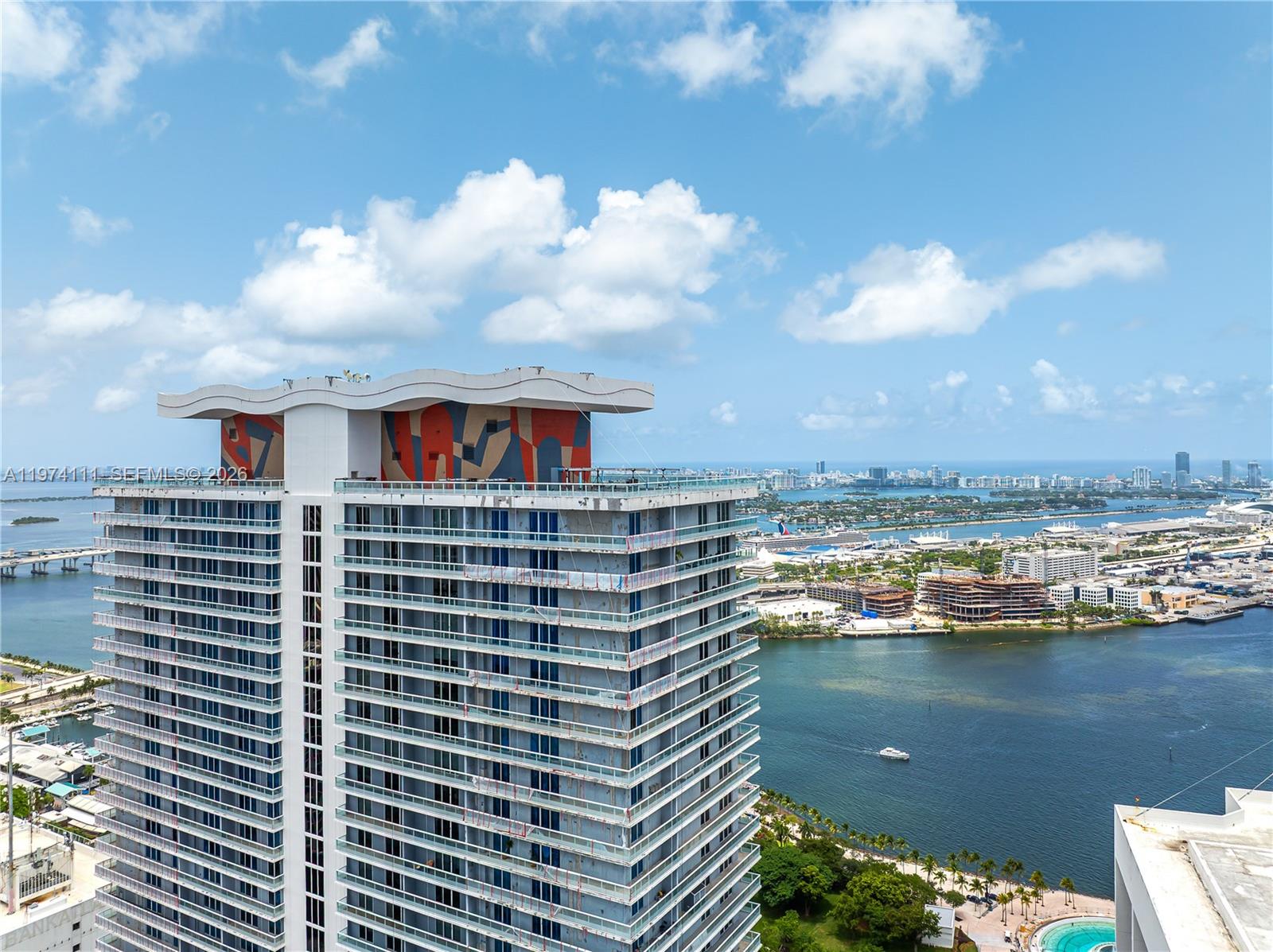 An aerial view shows a high-rise building with a colorful mural on its roof deck — 50 Biscayne Blvd # 3106, Miami FL 33132, MIAMI, FL