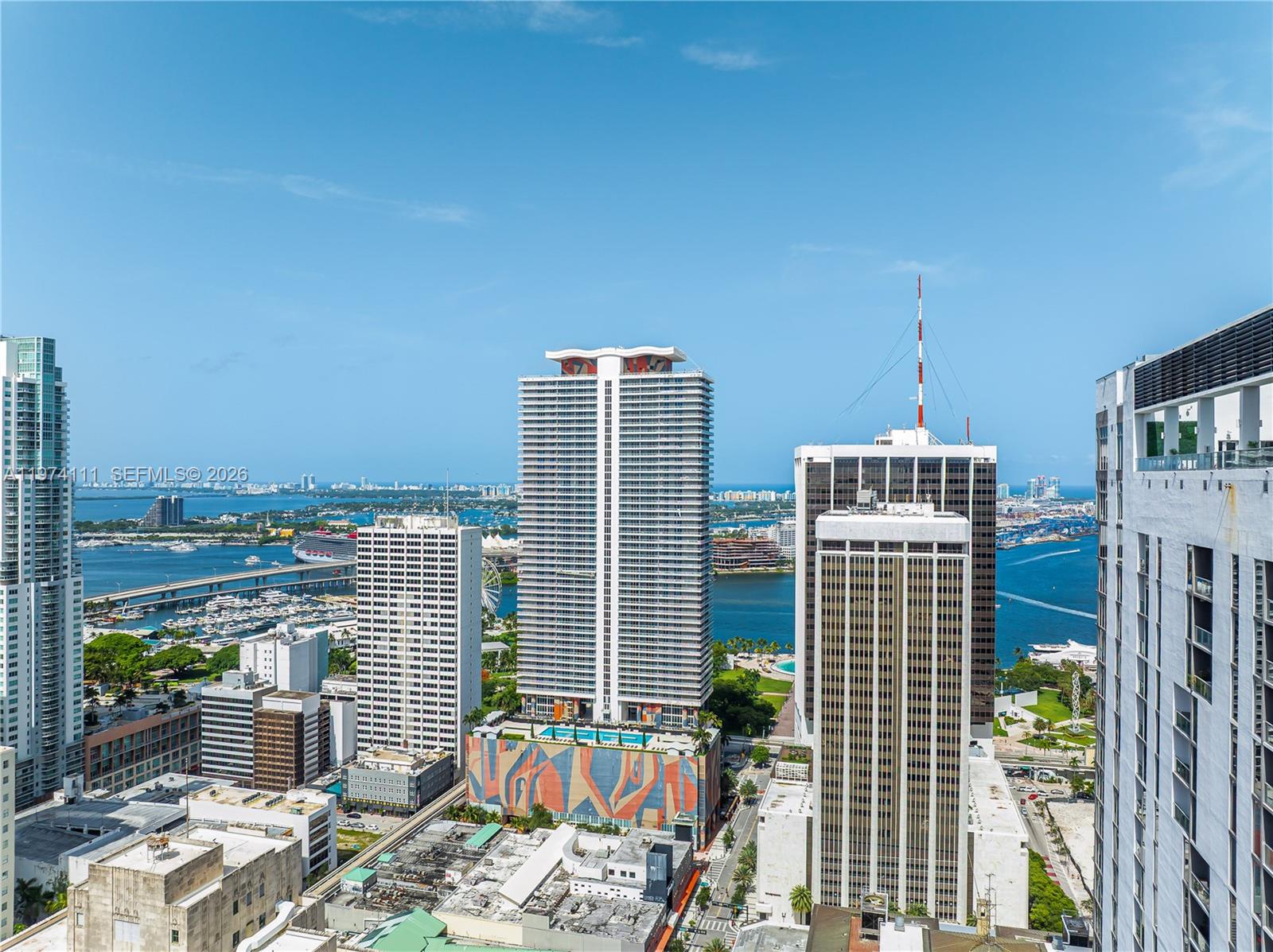An elevated exterior view shows several high-rise buildings and a bay with boats — 50 Biscayne Blvd # 3106, Miami FL 33132, MIAMI, FL