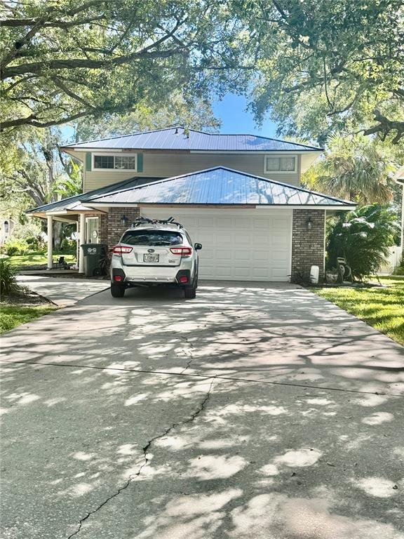 A two-story house with a metal roof and a silver SUV parked in the driveway — 6812 ARBOR OAKS DRIVE, BRADENTON, FL