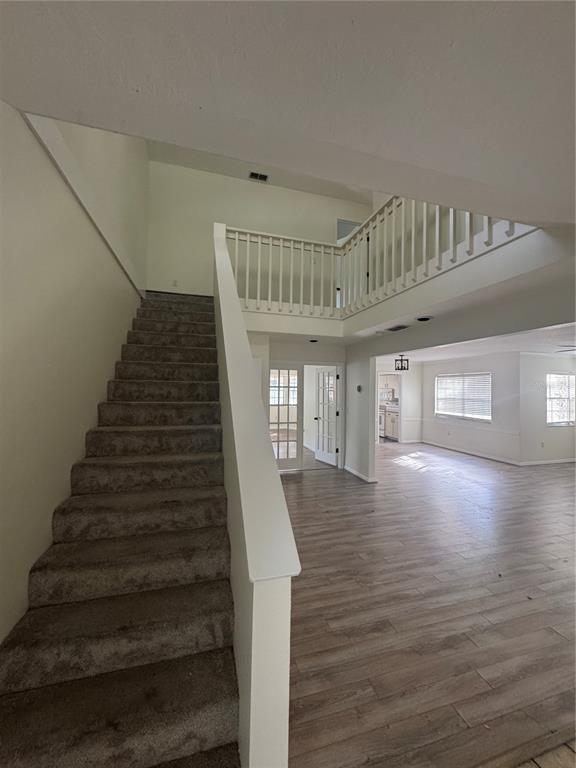 An interior view shows a carpeted staircase leading to a landing with a white railing — 6812 ARBOR OAKS DRIVE, BRADENTON, FL