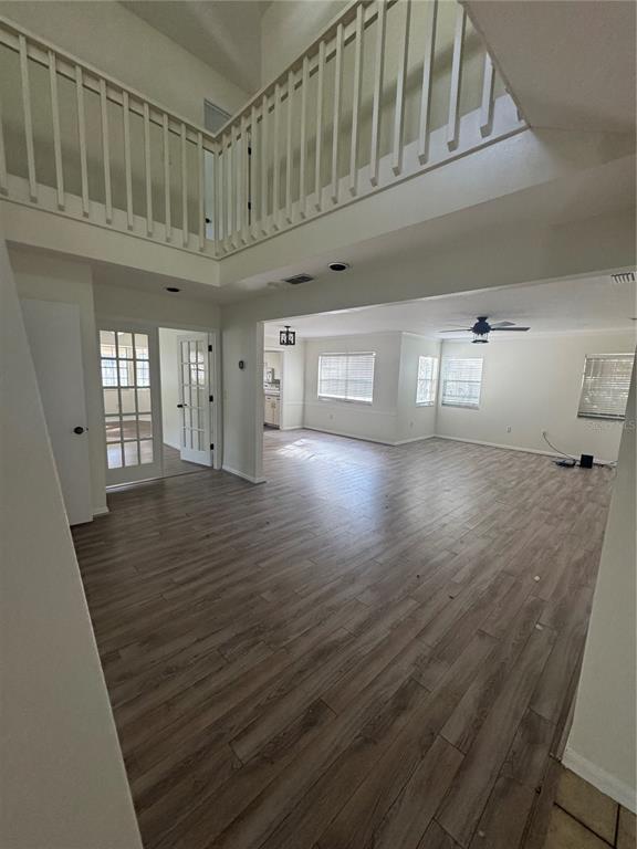 An open-concept living area features wood-look flooring, a two-story ceiling, and a white wooden railing — 6812 ARBOR OAKS DRIVE, BRADENTON, FL