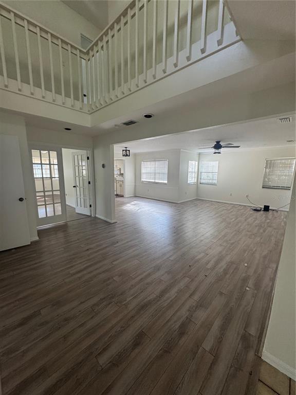 A spacious living area with wood-look flooring, a high ceiling, and a white wooden staircase railing — 6812 ARBOR OAKS DRIVE, BRADENTON, FL