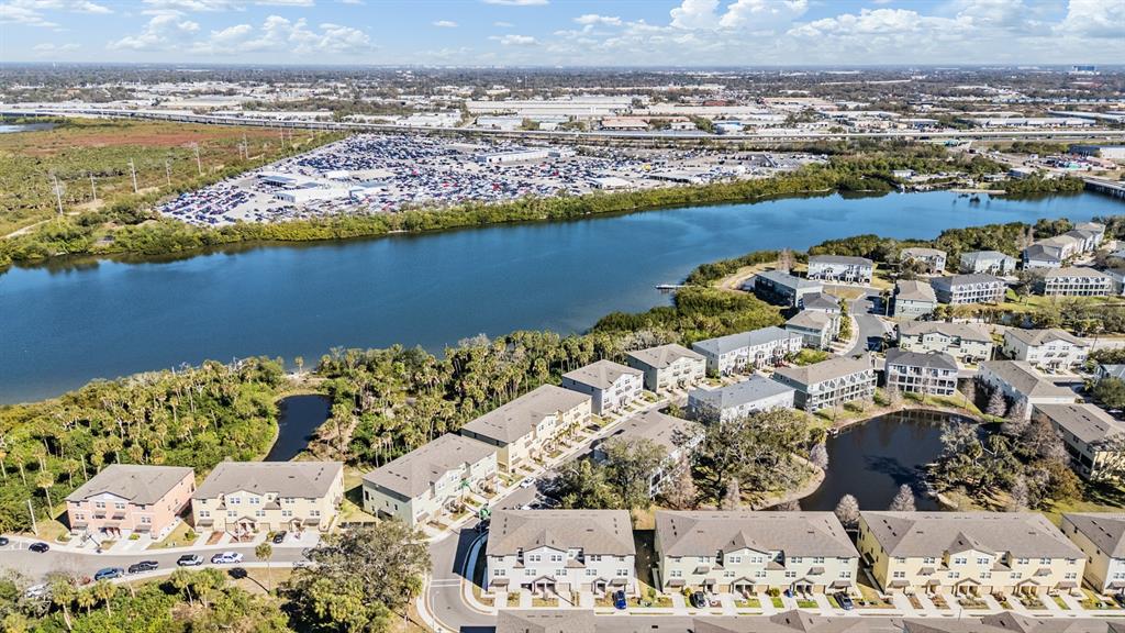 An aerial view shows a residential complex with multi-story buildings situated near a large lake — 4607 TUSCAN LOON DRIVE, TAMPA, FL