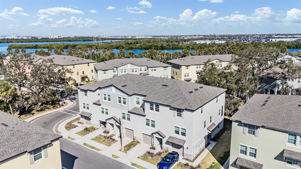 An aerial view shows a multi-story residential building with a gray roof and light-colored siding — 4607 TUSCAN LOON DRIVE, TAMPA, FL