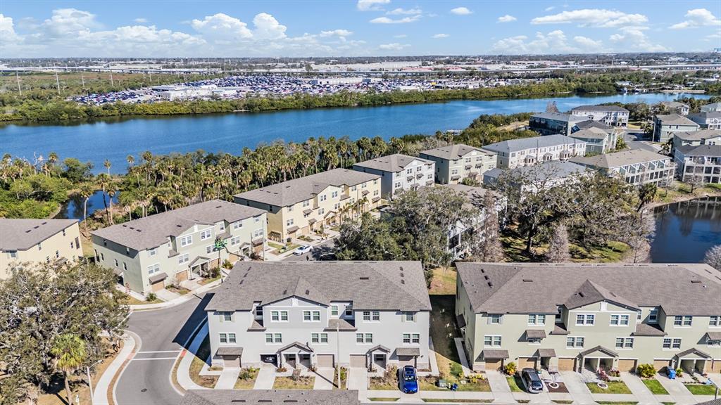 An aerial view shows multiple multi-story townhome buildings situated near a body of water — 4607 TUSCAN LOON DRIVE, TAMPA, FL