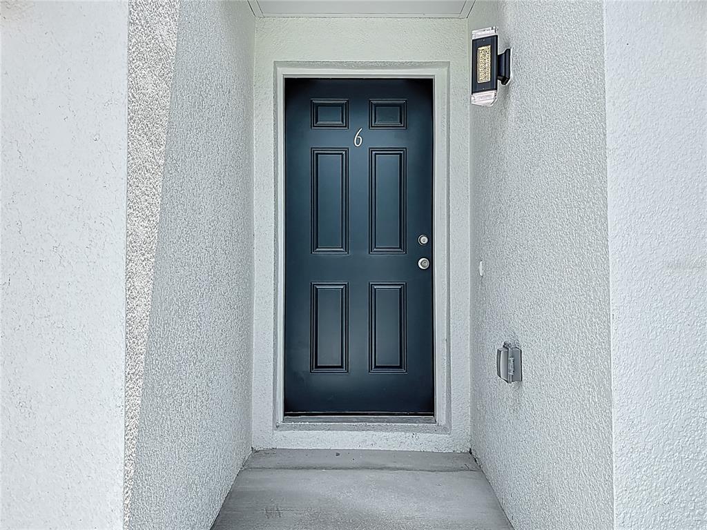 A black six-panel front door with the number six is set within a white alcove — 326 S GROSSE AVENUE UNIT 2, TARPON SPRINGS, FL