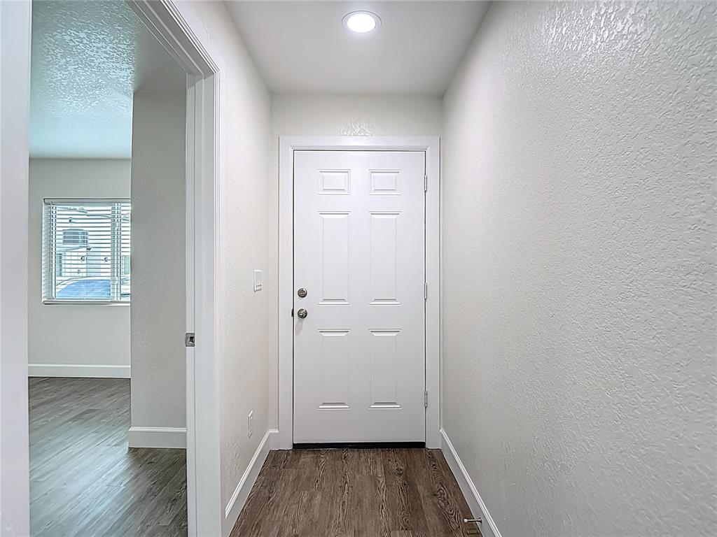 An entryway features a white six-panel door, light gray walls, and wood-look flooring — 326 S GROSSE AVENUE UNIT 2, TARPON SPRINGS, FL