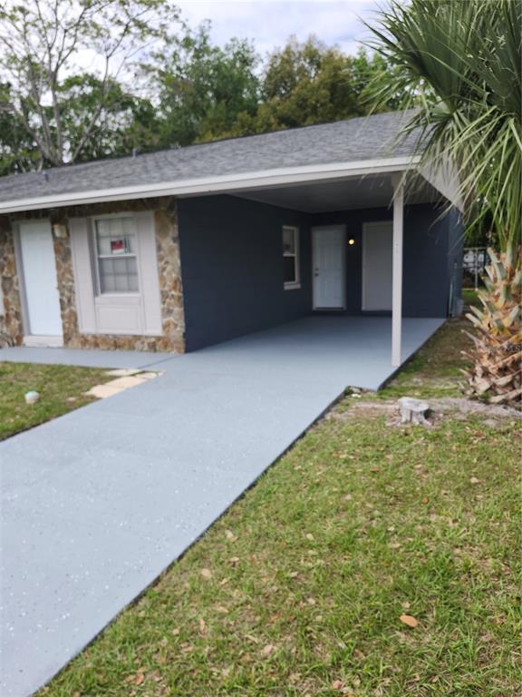 A single-story house exterior features a stone facade, dark blue paint, and a covered carport — 417 BENITA STREET, KISSIMMEE, FL