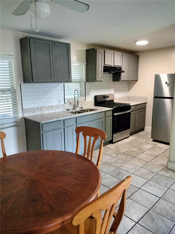 A kitchen features gray cabinets, white subway tile backsplash, stainless steel appliances, and tile flooring — 417 BENITA STREET, KISSIMMEE, FL