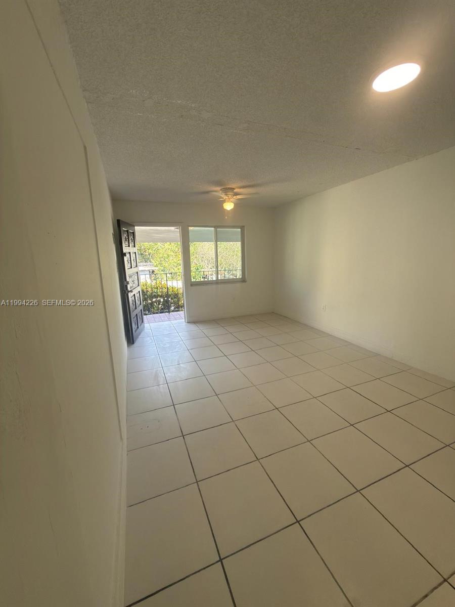 An empty room features white walls, a tiled floor, a ceiling fan, and a doorway — 2622 NW 24th St # 3B, Miami FL 33142, MIAMI, FL