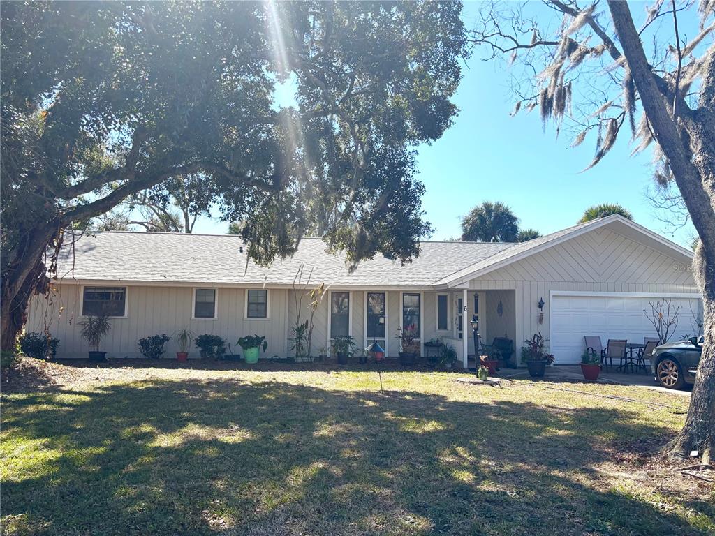 A single-story house with light-colored vertical siding, a two-car garage, and large shade trees — 6 FAIRGREEN AVENUE, NEW SMYRNA BEACH, FL