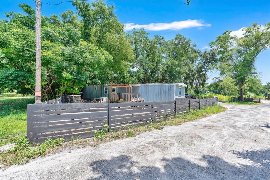 A mobile home sits behind a dark horizontal wooden fence on a gravel lot — 4850 W PONKAN ROAD, APOPKA, FL