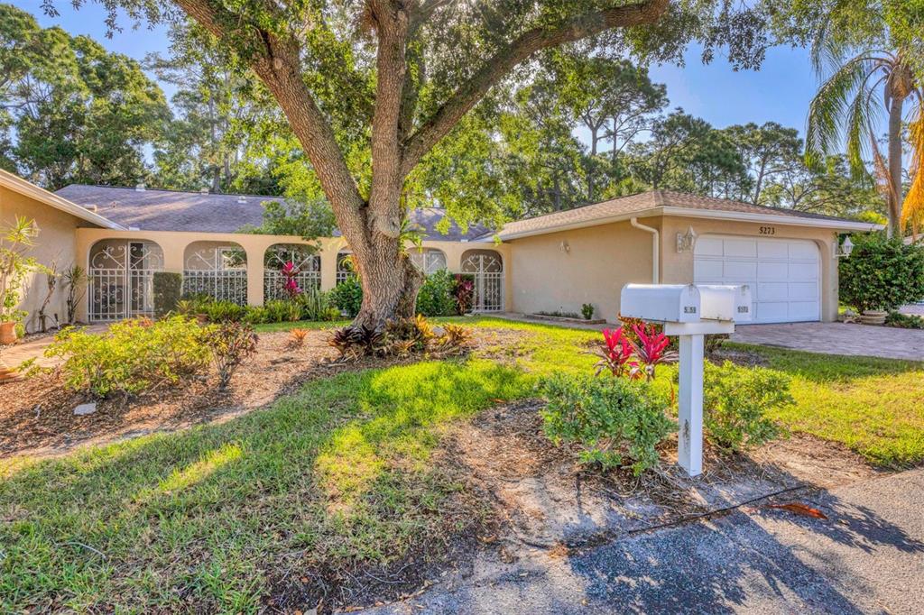 A single-story house with a white garage, arched entryways, and a large tree in front — 5273 VILLA MAJORCA COURT UNIT 25, SARASOTA, FL