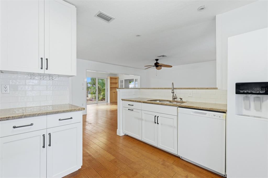 A kitchen with white cabinets, granite countertops, and hardwood floors opens to a living area — 5273 VILLA MAJORCA COURT UNIT 25, SARASOTA, FL