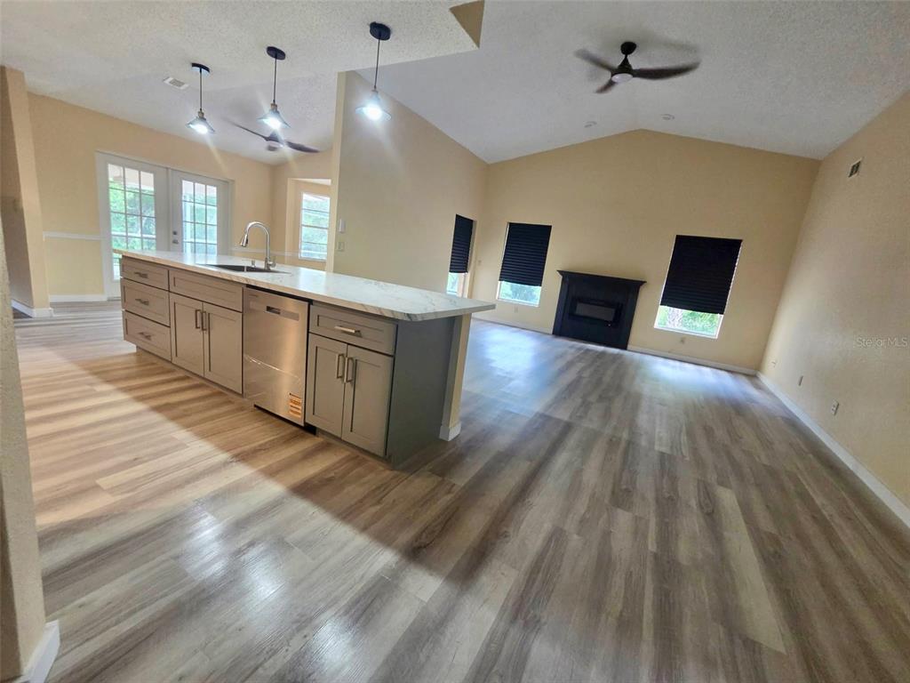 A kitchen with a marble-topped island and gray cabinets opens into a living area — 5137 MONTFORD CIRCLE, SPRING HILL, FL