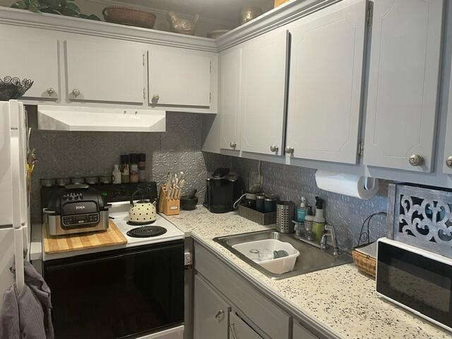 A kitchen features gray cabinets, a speckled countertop, a stove, and a stainless steel sink — 620 W Horizons W # 207, Boynton Beach FL 33435, BOYNTON BEACH, FL