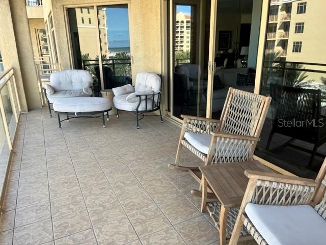 A tiled balcony features outdoor seating, including armchairs, a footstool, and rocking chairs — 11 BAYMONT STREET UNIT 504, CLEARWATER BEACH, FL