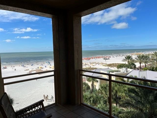 A balcony overlooks a sandy beach with palm trees and the ocean under a blue sky — 11 BAYMONT STREET UNIT 504, CLEARWATER BEACH, FL