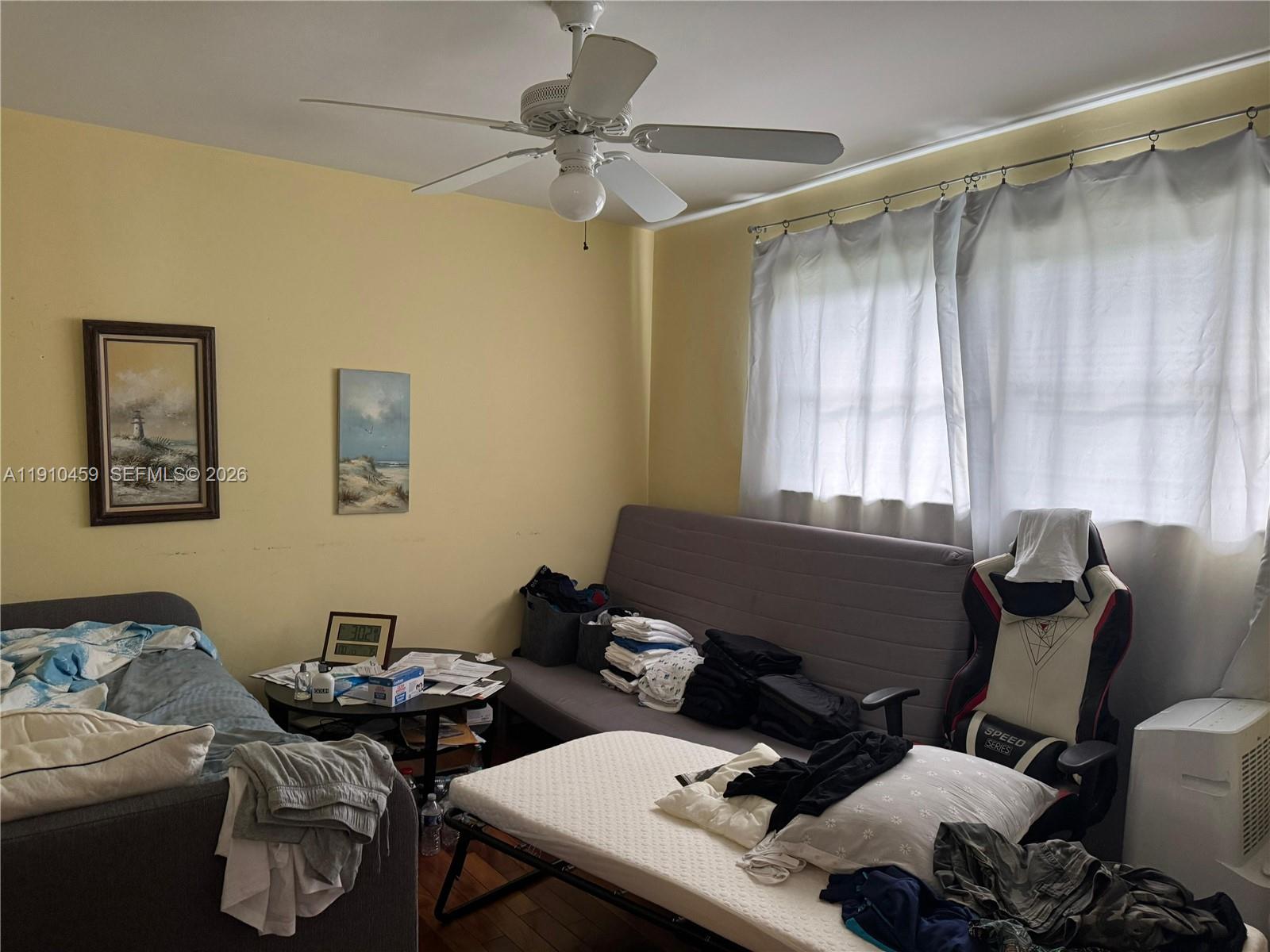 A bedroom features a ceiling fan, two sofas, a folding bed, and a gaming chair — 2444 Polk St # 210, Hollywood FL 33020, HOLLYWOOD, FL
