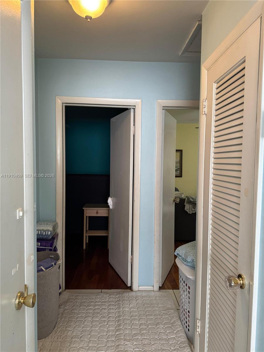 A hallway features two open doorways, a louvered closet door, and light blue walls — 2444 Polk St # 210, Hollywood FL 33020, HOLLYWOOD, FL