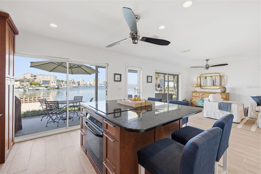 A kitchen island with a dark countertop overlooks a patio and a waterfront view — 400 LARBOARD WAY UNIT 105, CLEARWATER BEACH, FL