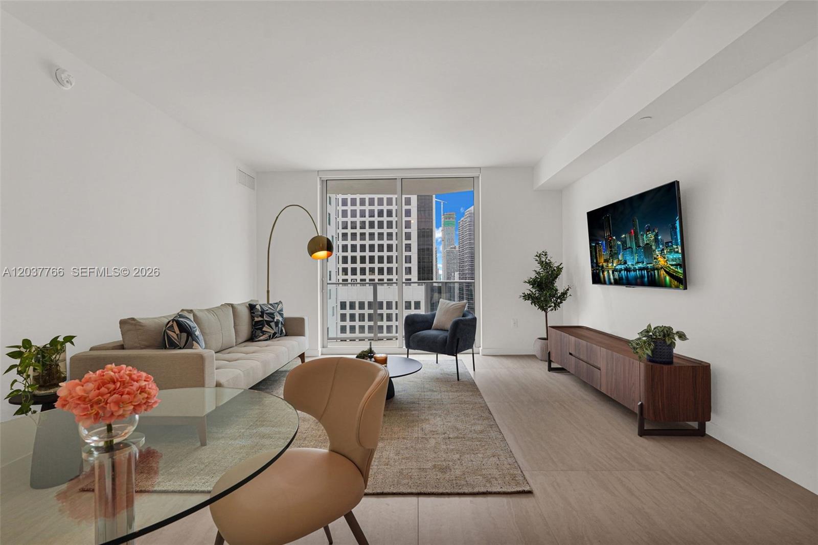 A modern living room features a beige sofa, a glass dining table, and city views — 77 SE 5th St # 3714, Miami FL 33131, MIAMI, FL