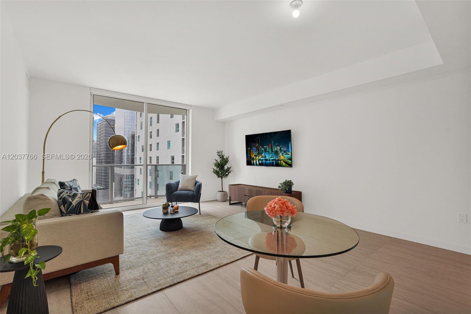 A modern living and dining area features a glass table, sofa, and floor-to-ceiling windows — 77 SE 5th St # 3714, Miami FL 33131, MIAMI, FL