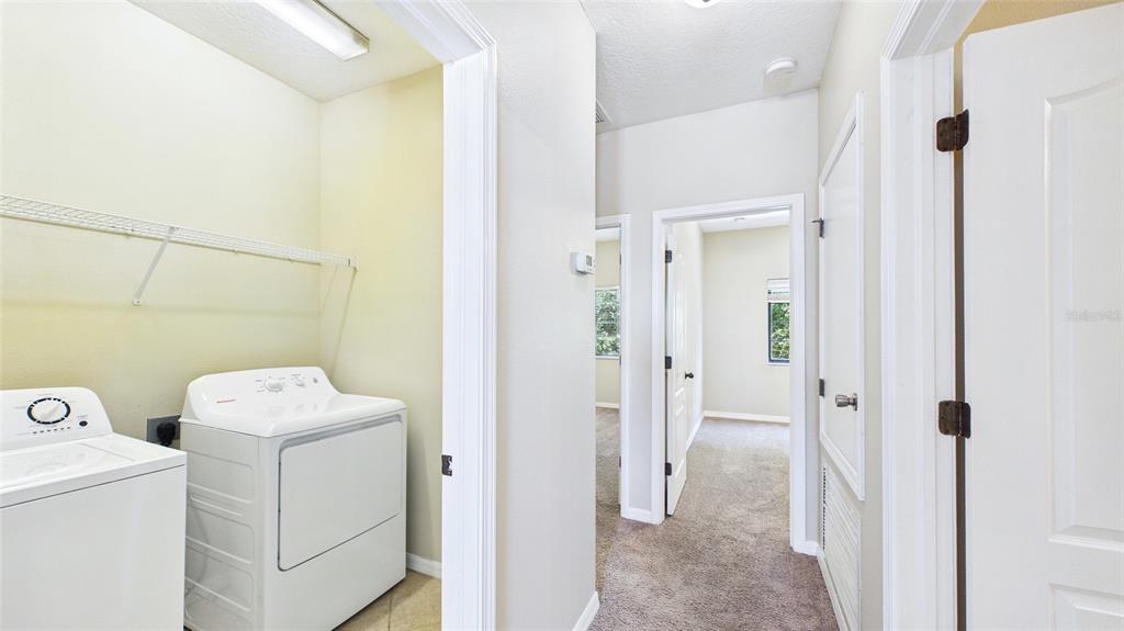 A laundry room with a washer and dryer leads into a carpeted hallway with doorways — 13128 LOGAN CAPTIVA LANE, GIBSONTON, FL