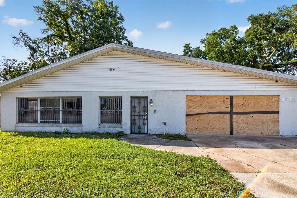 A single-story house with white siding, barred windows, and a boarded-up garage door — 421 N FREDERICK AVENUE, DAYTONA BEACH, FL