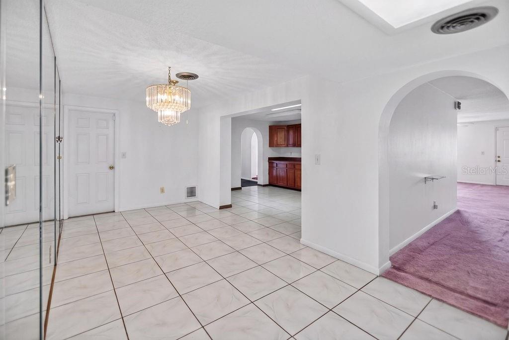 A dining area with white tile floors, a crystal chandelier, and an arched entryway — 421 N FREDERICK AVENUE, DAYTONA BEACH, FL