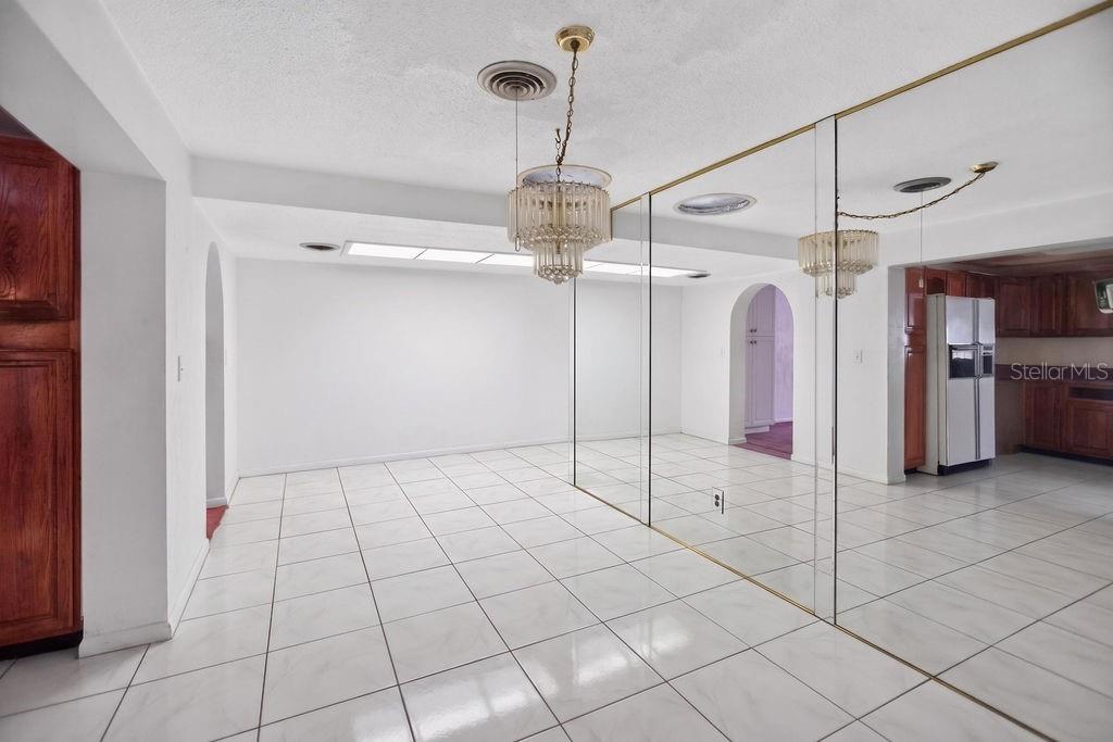 A dining area features white tile flooring, a crystal chandelier, and a large mirrored wall — 421 N FREDERICK AVENUE, DAYTONA BEACH, FL