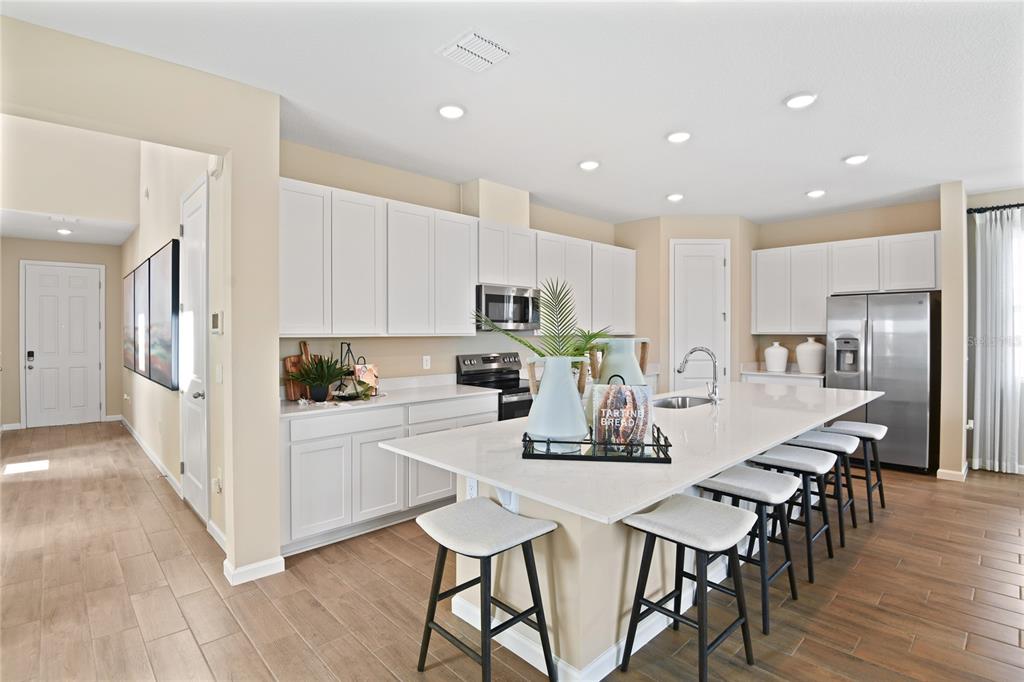 A modern kitchen features white cabinetry, stainless steel appliances, and a large central island — 2910 27TH AVENUE E, PALMETTO, FL