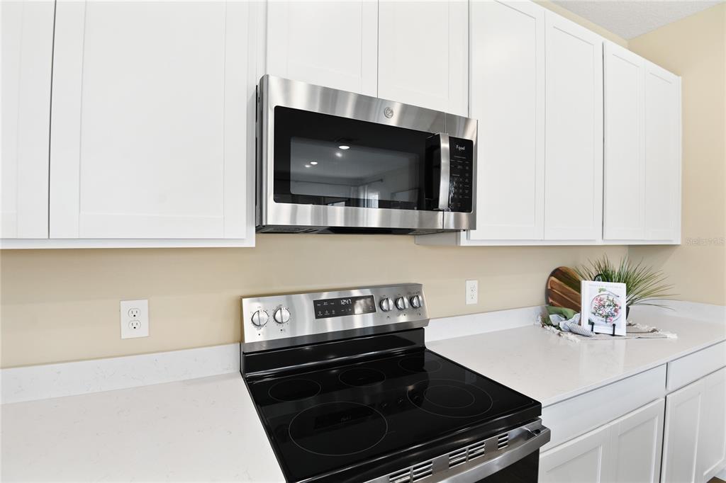 A kitchen features white cabinets, stainless steel appliances, and light-colored quartz countertops — 2910 27TH AVENUE E, PALMETTO, FL