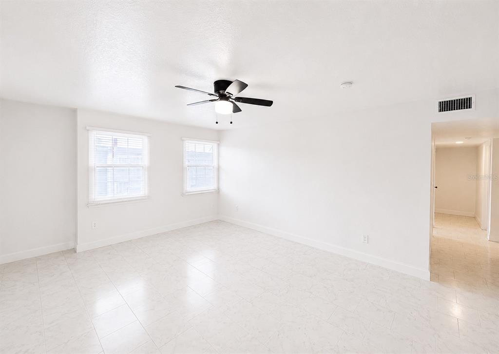 A bright, empty room features white walls, tile flooring, two windows, and a ceiling fan — 2751 L B MCLEOD ROAD UNIT C, ORLANDO, FL