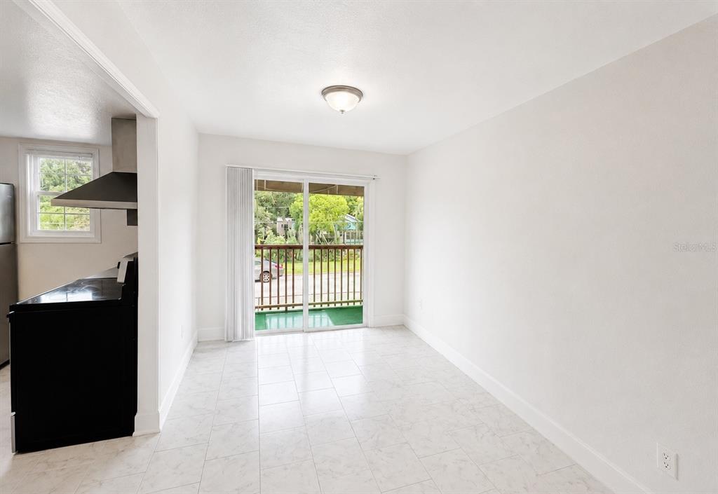 A dining area with white tile floors, a sliding glass door, and an adjacent kitchen — 2751 L B MCLEOD ROAD UNIT C, ORLANDO, FL